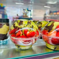 Clear cups filled with strawberries, cream, and chocolate