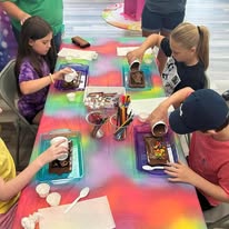 Kids making chocolate treats along a bright table at Sugar Shenanigans